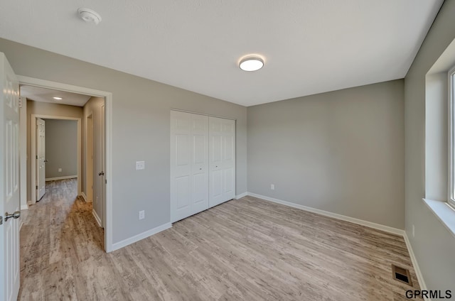 unfurnished bedroom featuring light wood-type flooring and a closet