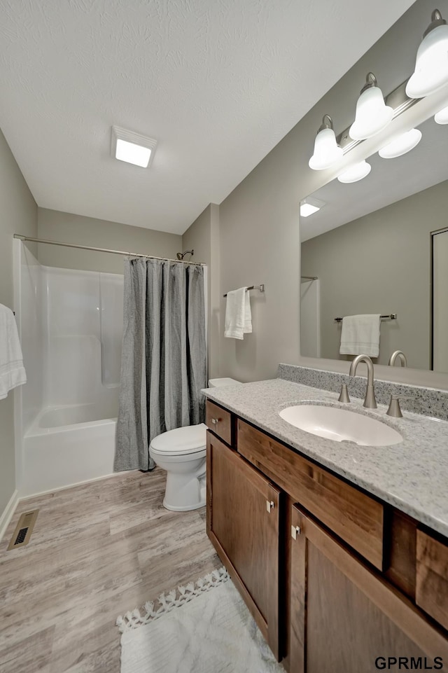 bathroom with toilet, vanity, a textured ceiling, and hardwood / wood-style flooring