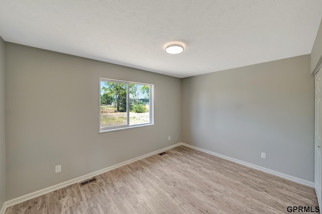 spare room with light wood-type flooring and a textured ceiling