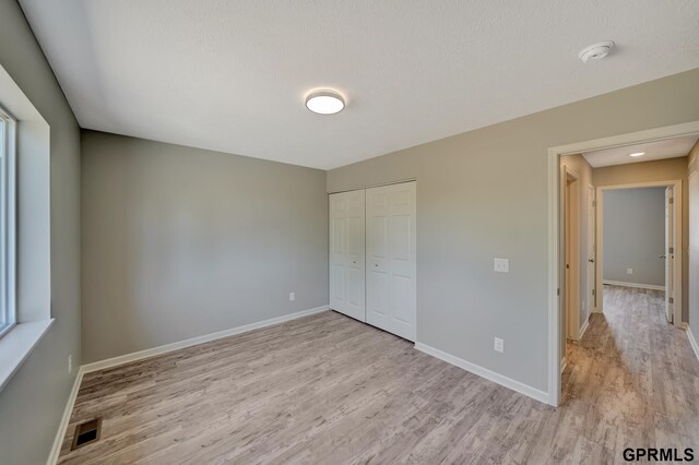 unfurnished bedroom featuring light hardwood / wood-style flooring and a closet