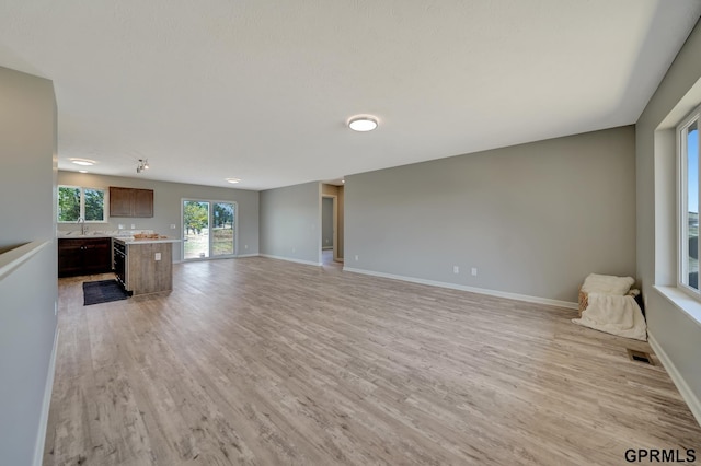 unfurnished living room featuring light hardwood / wood-style flooring and sink