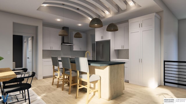 kitchen with light hardwood / wood-style flooring, a center island with sink, wall chimney range hood, and stainless steel fridge