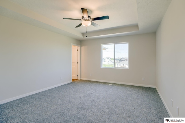 carpeted empty room featuring a raised ceiling and ceiling fan