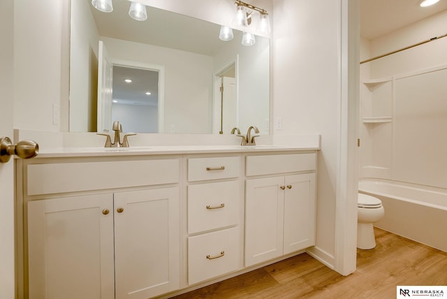 full bathroom featuring hardwood / wood-style flooring, washtub / shower combination, vanity, and toilet