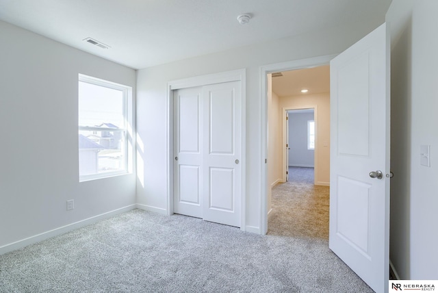 unfurnished bedroom featuring light carpet and a closet