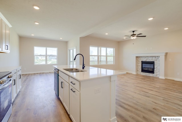 kitchen with sink, appliances with stainless steel finishes, an island with sink, light hardwood / wood-style floors, and white cabinets