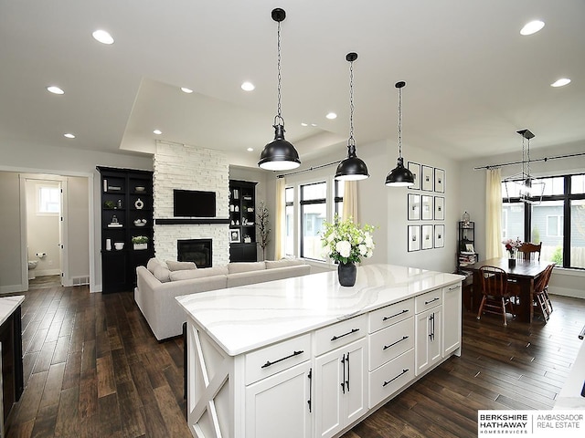 kitchen with decorative light fixtures, a fireplace, white cabinetry, and a healthy amount of sunlight