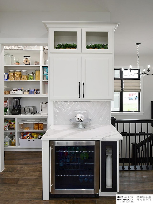 bar featuring hanging light fixtures, white cabinets, beverage cooler, and light stone countertops