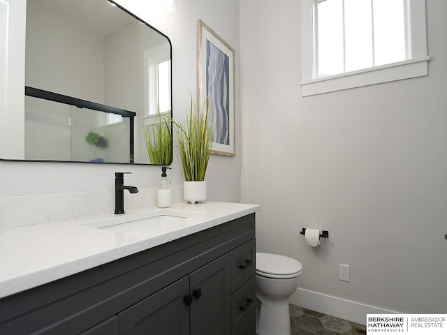 bathroom with vanity, toilet, a shower with door, and a healthy amount of sunlight