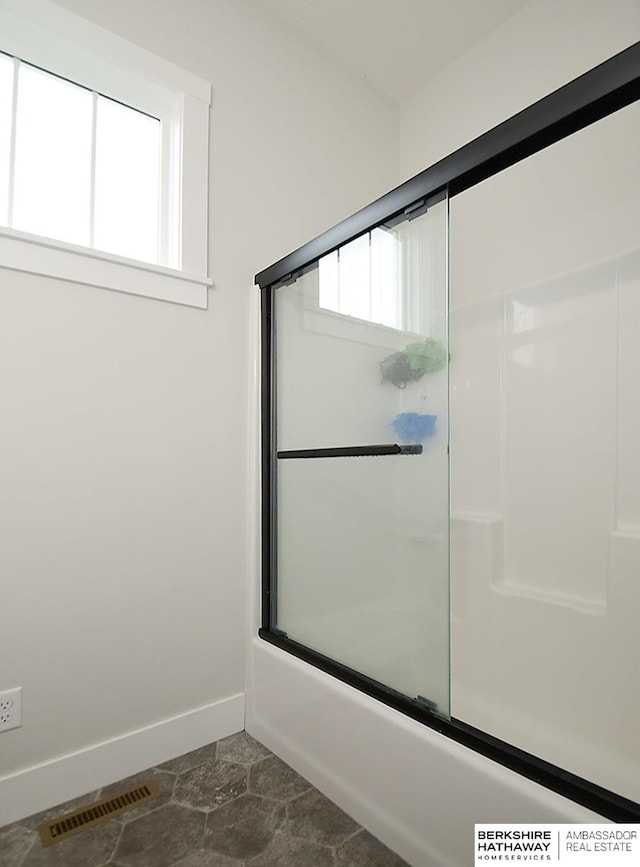 bathroom featuring combined bath / shower with glass door