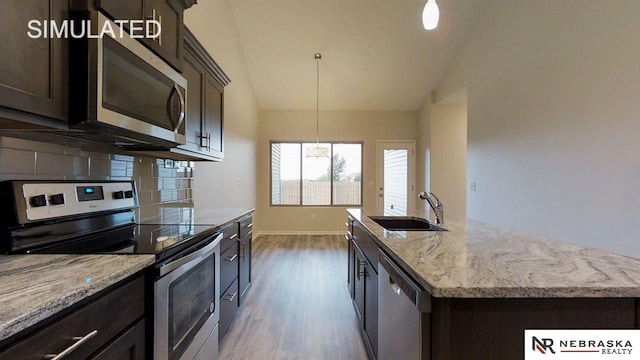 kitchen featuring pendant lighting, sink, lofted ceiling, a center island with sink, and appliances with stainless steel finishes