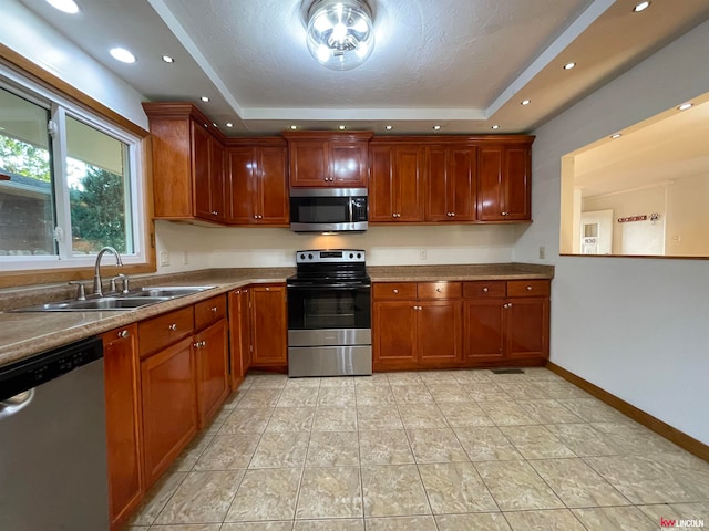 kitchen with stainless steel appliances, a raised ceiling, light tile patterned floors, and sink