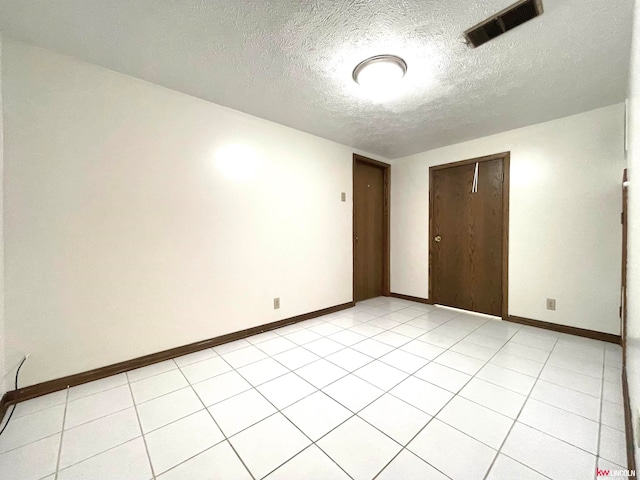 tiled spare room featuring a textured ceiling