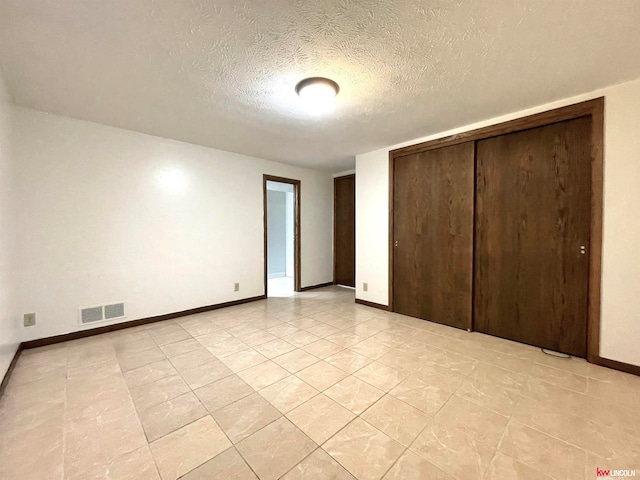 unfurnished bedroom with a textured ceiling and a closet