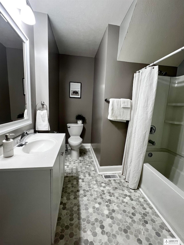 full bathroom featuring vanity, shower / tub combo, toilet, and a textured ceiling