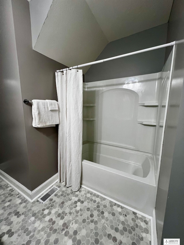 bathroom featuring shower / bath combo and vaulted ceiling