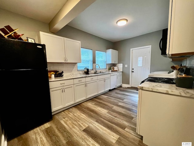 kitchen with light hardwood / wood-style floors, white cabinetry, black fridge, and white dishwasher