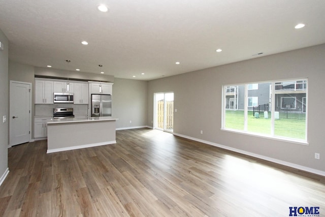 kitchen featuring white cabinets, a center island, light hardwood / wood-style floors, and appliances with stainless steel finishes