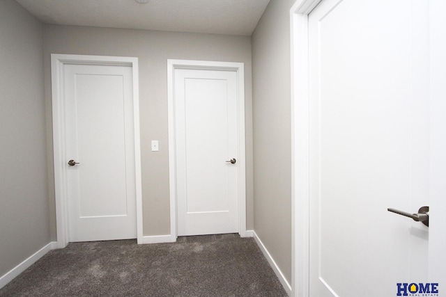 hallway featuring dark colored carpet