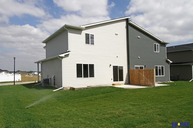 back of house with central air condition unit and a lawn