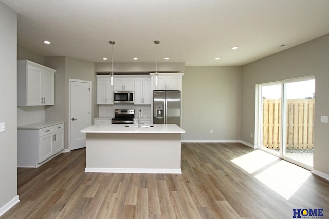 kitchen with pendant lighting, sink, a center island with sink, and stainless steel appliances