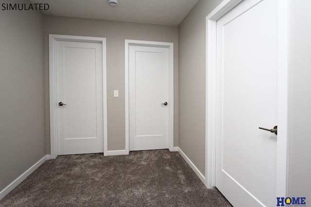 hallway featuring a textured ceiling and dark colored carpet