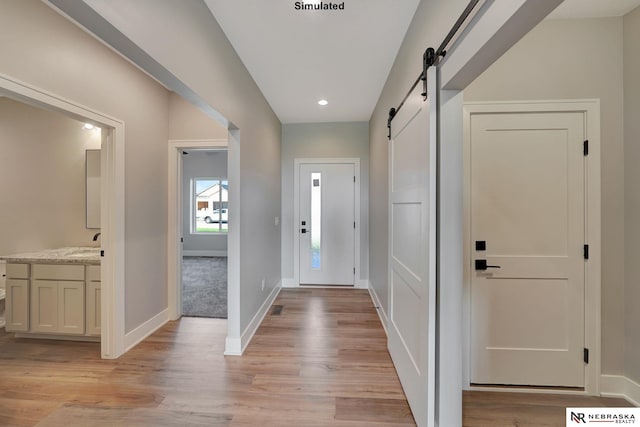 entryway with sink, light wood-type flooring, and a barn door