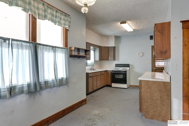 kitchen with a textured ceiling, sink, white range with gas cooktop, and a wealth of natural light