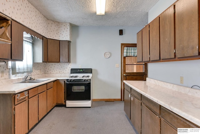 kitchen featuring a textured ceiling, sink, light carpet, and gas range gas stove