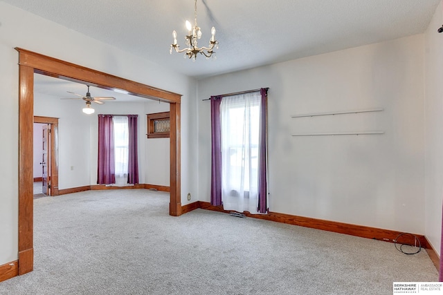 spare room with a healthy amount of sunlight, carpet, and ceiling fan with notable chandelier