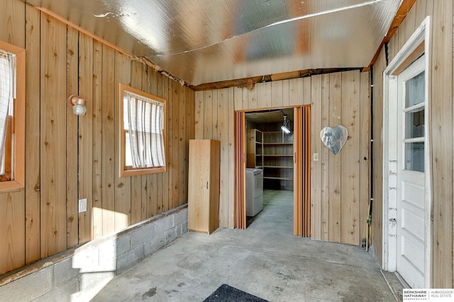 empty room featuring washer / clothes dryer and wood walls