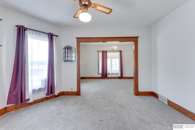 spare room featuring light carpet and ceiling fan with notable chandelier