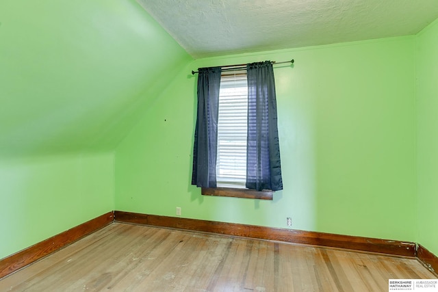 bonus room with a textured ceiling, hardwood / wood-style floors, and vaulted ceiling