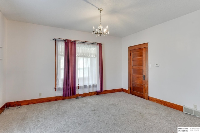 spare room featuring carpet flooring and an inviting chandelier