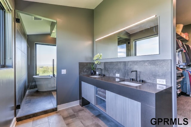 bathroom featuring vanity, tasteful backsplash, vaulted ceiling, a bathing tub, and tile patterned flooring