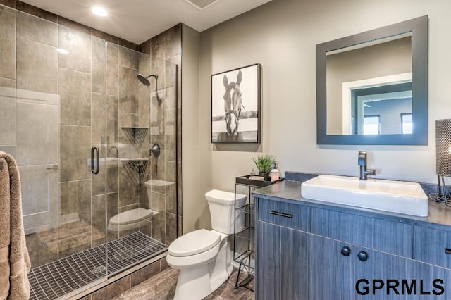 bathroom featuring a shower with shower door, vanity, and toilet