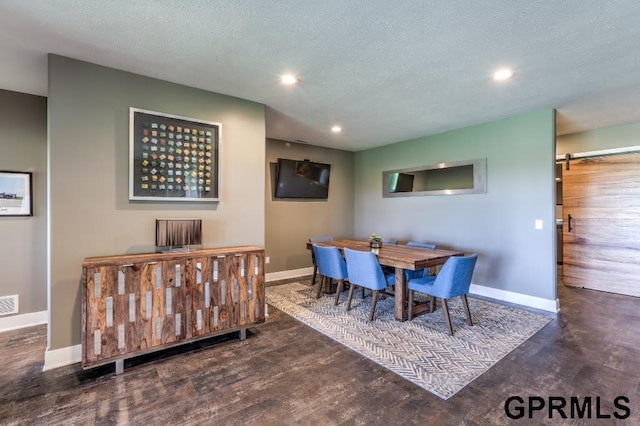 dining room featuring a barn door, a textured ceiling, and dark hardwood / wood-style flooring