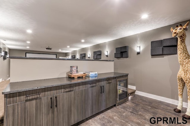 bar featuring dark stone counters, dark hardwood / wood-style floors, and beverage cooler