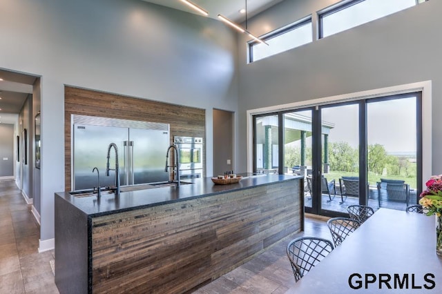 kitchen featuring built in refrigerator, hardwood / wood-style flooring, a towering ceiling, and sink