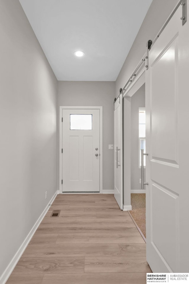 doorway to outside featuring a barn door and light hardwood / wood-style flooring