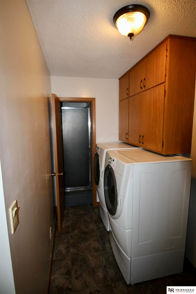 laundry area featuring cabinets, a textured ceiling, and washing machine and dryer