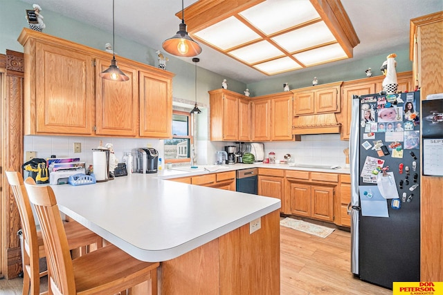 kitchen featuring appliances with stainless steel finishes, light hardwood / wood-style floors, kitchen peninsula, a kitchen bar, and decorative light fixtures