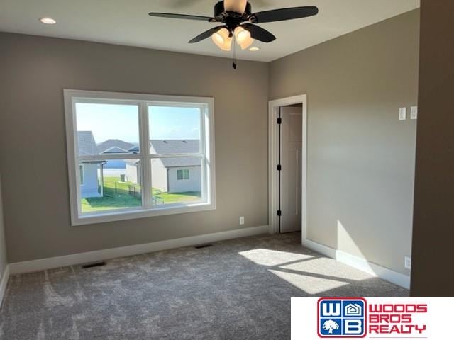 spare room with dark colored carpet and ceiling fan