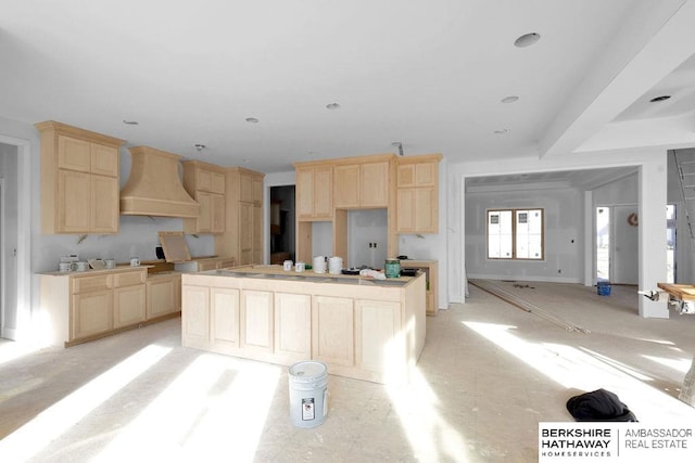 kitchen with a kitchen island, wall chimney range hood, and light brown cabinetry