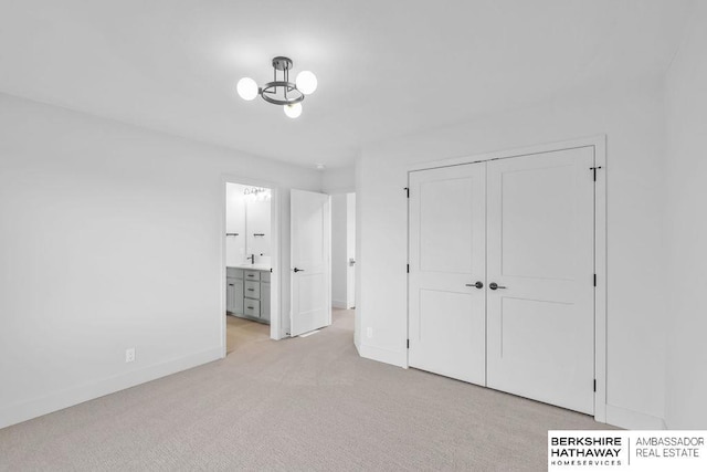 unfurnished bedroom featuring a chandelier, light carpet, connected bathroom, and a closet