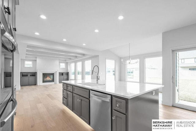 kitchen with sink, light hardwood / wood-style flooring, stainless steel dishwasher, a chandelier, and a center island with sink