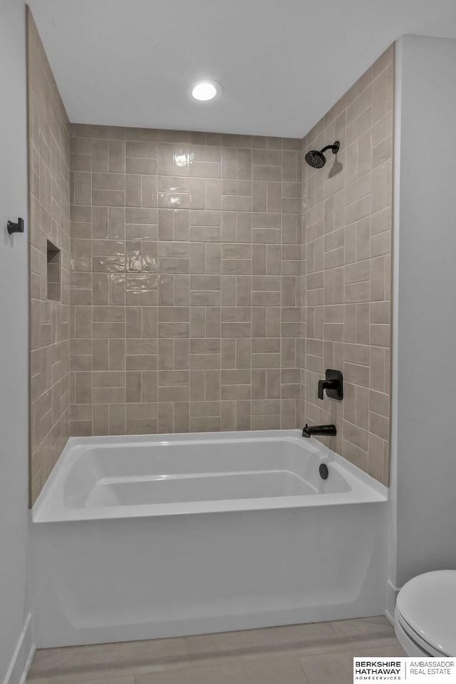 bathroom with toilet and tiled shower / bath