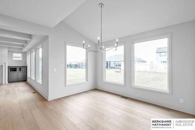 unfurnished dining area with an inviting chandelier, lofted ceiling, and light hardwood / wood-style flooring