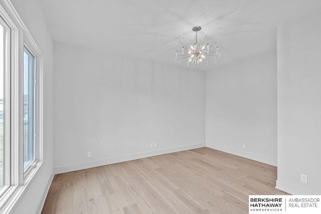 empty room with a chandelier, light hardwood / wood-style floors, and a wealth of natural light