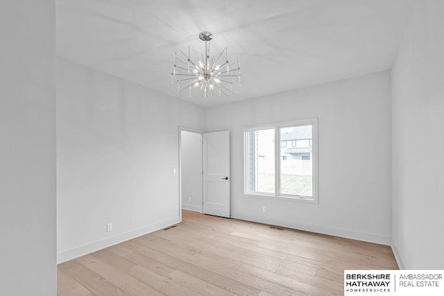 unfurnished room featuring a chandelier and light hardwood / wood-style floors